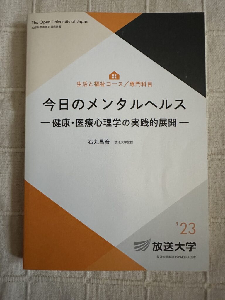 「放送大学のテキスト『今日のメンタルヘルス ―健康・医療心理学の実践的展開―』の表紙。オレンジと黒を配した構成」