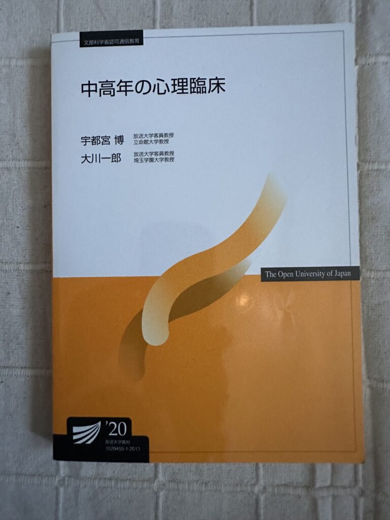 「放送大学のテキスト『中高年の心理臨床』の表紙。やさしいオレンジ系のグラデーションが使われたデザイン」