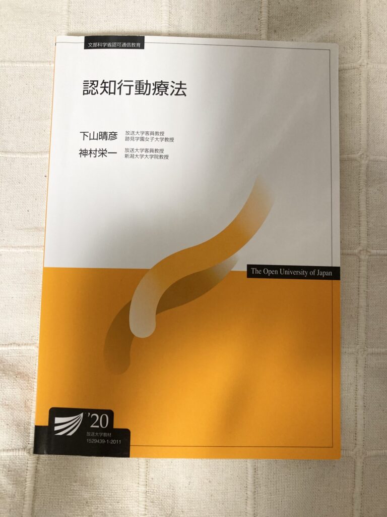 「放送大学のテキスト『認知行動療法』の表紙。オレンジ色を基調としたデザインで、著者は下山晴彦氏と神村栄一氏」