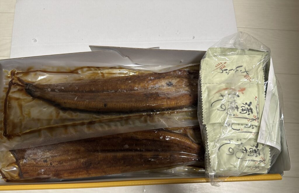 真空パックされた国産うなぎ蒲焼6尾と、添付のたれ・山椒の小袋がセットになっているふるさと納税返礼品。